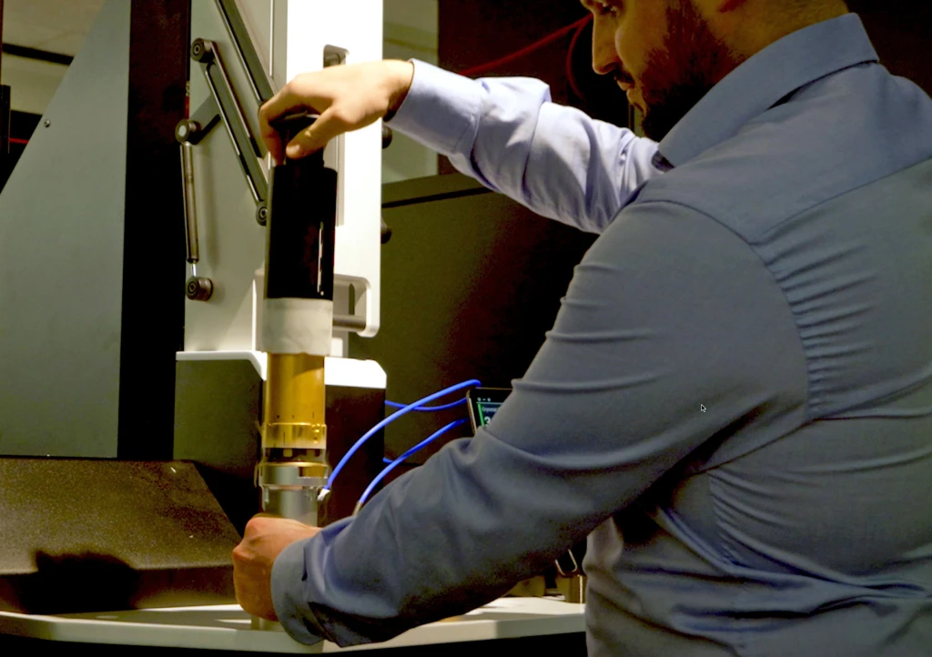 Researcher connecting cooling lines to a cryostat sample probe assembly.