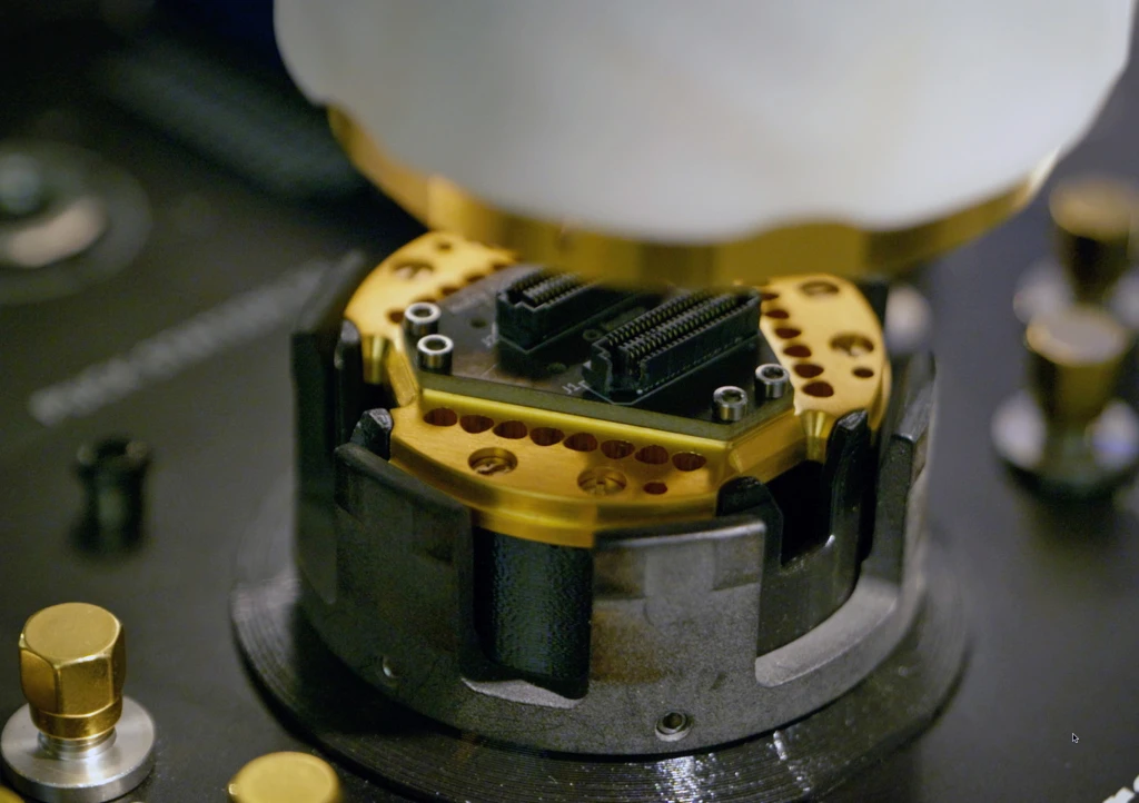 Macro view of a sample puck's gold-plated chip-carrier connectors in the cryostat's sample holder.