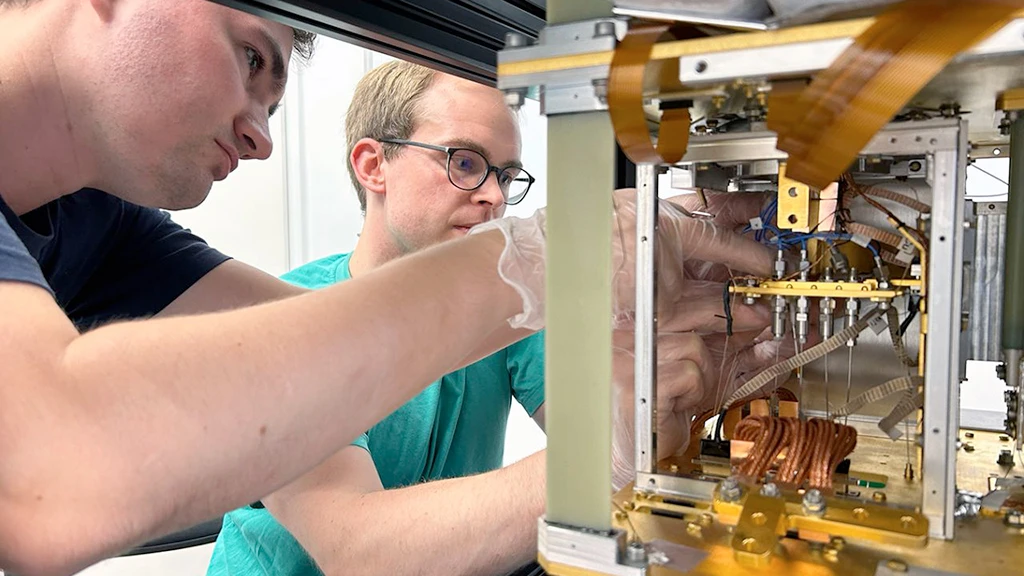 Two researchers wiring the sample stage of an S-Type Optical cryostat during installation.