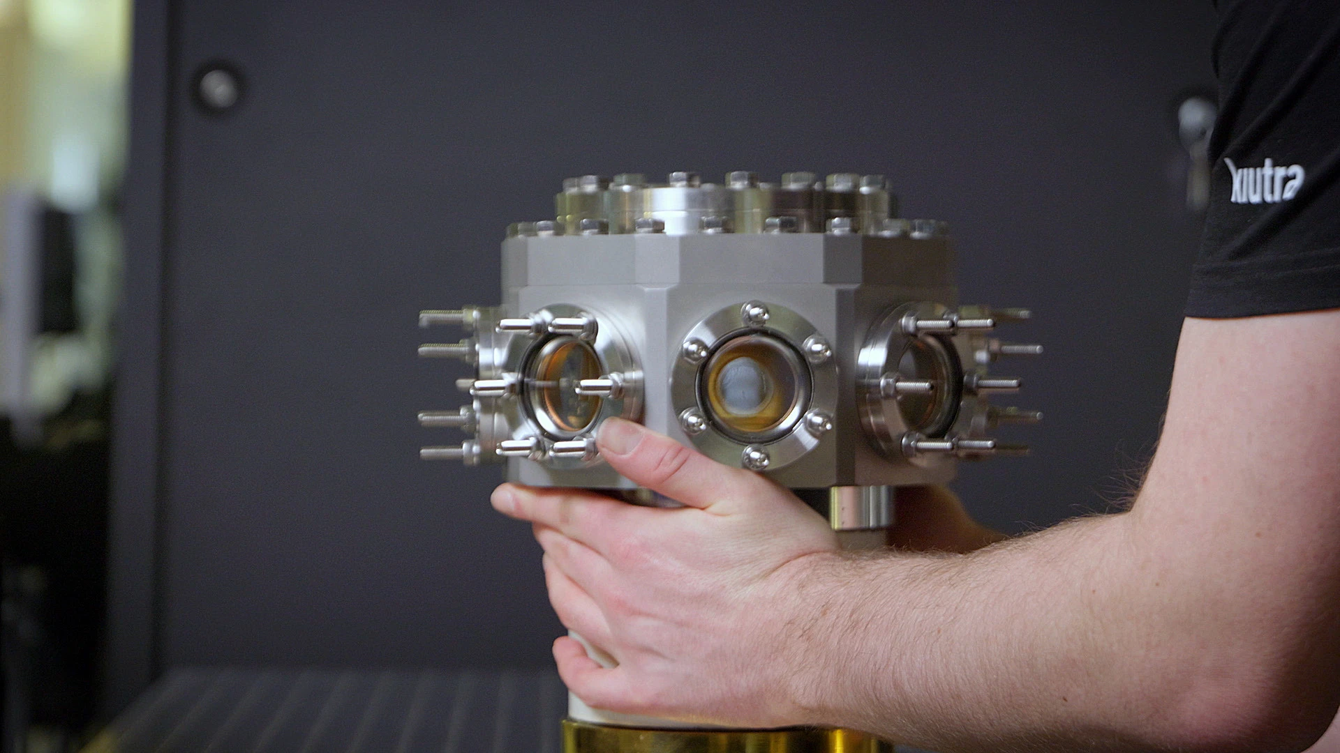 A kiutra engineer holding the T-Type Optical vacuum chamber, free-beam access ports on three sides