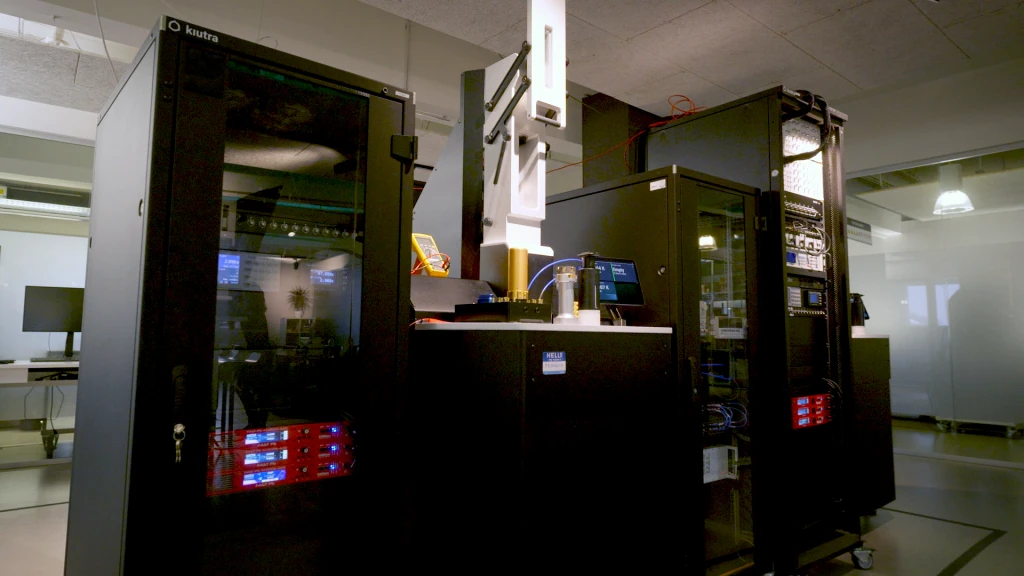 The kiutra characterization lab: two black L-Type Rapid cryostat racks with measurement electronics and a sample stage under a work lamp