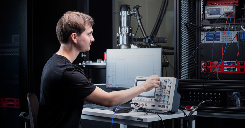 Person testing with a cryostat, electronics rack visible in the background.